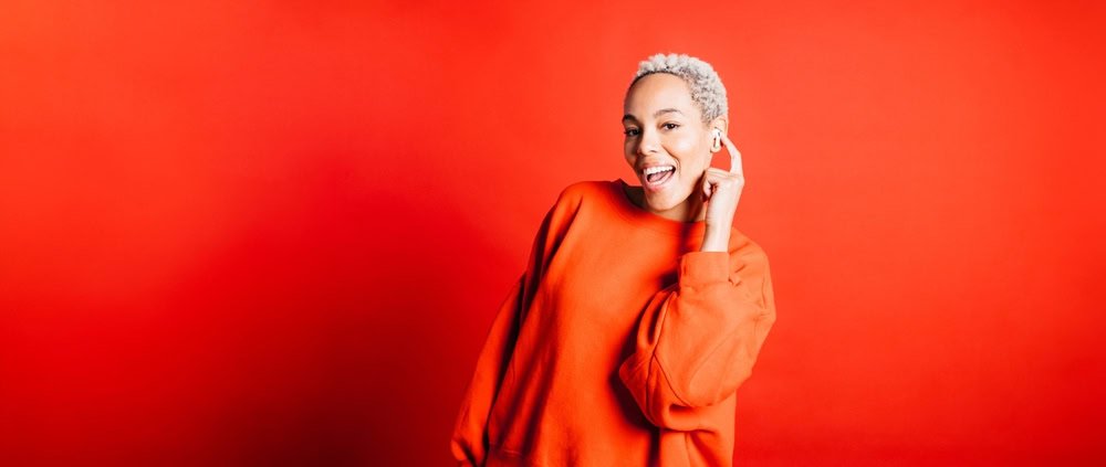 A happy young woman dancing with in-ear headphones and listening to a strategies for AI startups