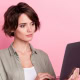Photo of a woman looking serious as she focuses on her laptop computer.