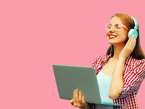 Picture of a modern young woman holding a laptop and listening to headphones