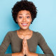 Photo of a cheerful young woman pressing her hands together in the prayer position