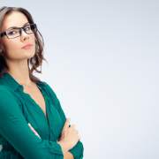 PR executive, woman, glasses, arms crossed, serious, brown hair, green shirt