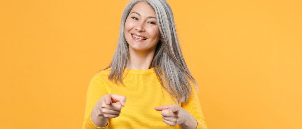 A smiling, cheerful woman pointing at the camera