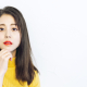 A young Asian woman resting her hand on her chin, making a decision about healthech brands